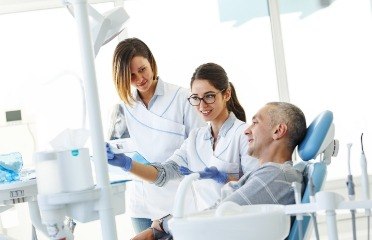 Instructor and dental assistant trainee talking to dental patient