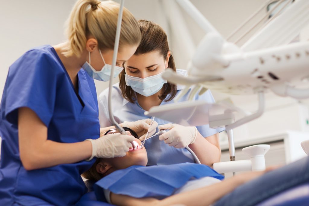 Closeup of dentist and dental assistant working on patient
