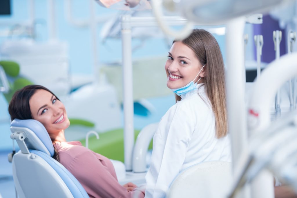 Dental assistant and patient smiling during appointment