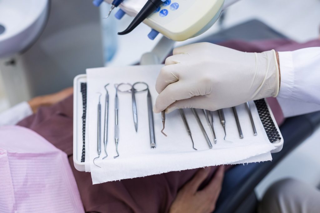 Dental assistant in gloves laying out dental instruments