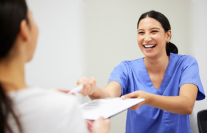 a dental assistant smiling as they help a patient 