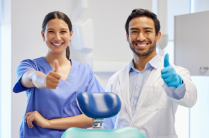 a dental assistant smiling and helping a dentist 