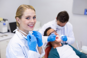 a dental assistant smiling while observing a dentist
